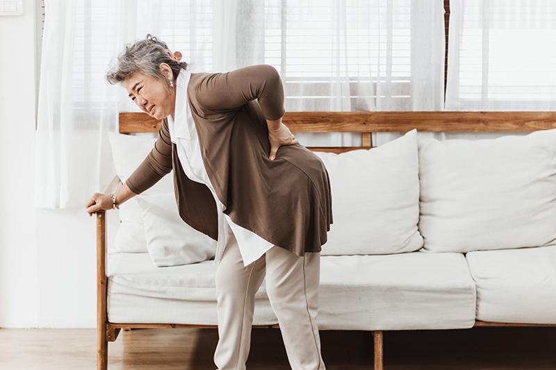 Woman experiencing lower back pain affecting mobility.
