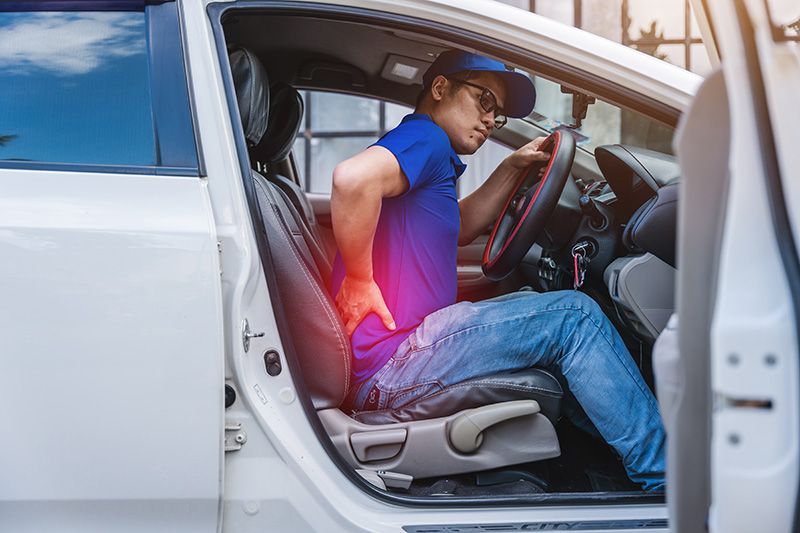 A man experiencing back pain while seated in a vehicle