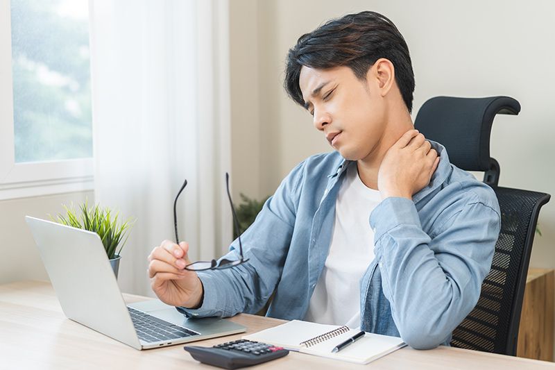 A man experiencing neck pain while working
